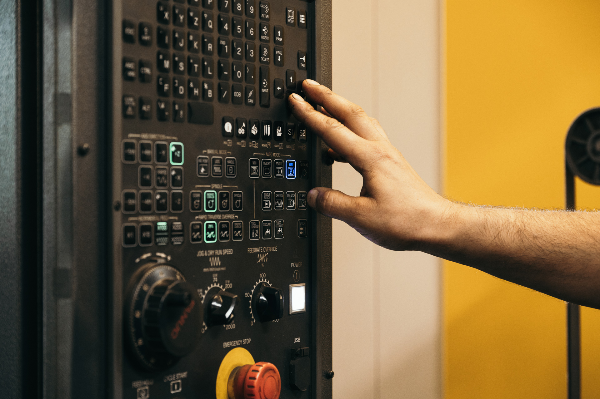 A hand adjusts settings on a fabricating machine
